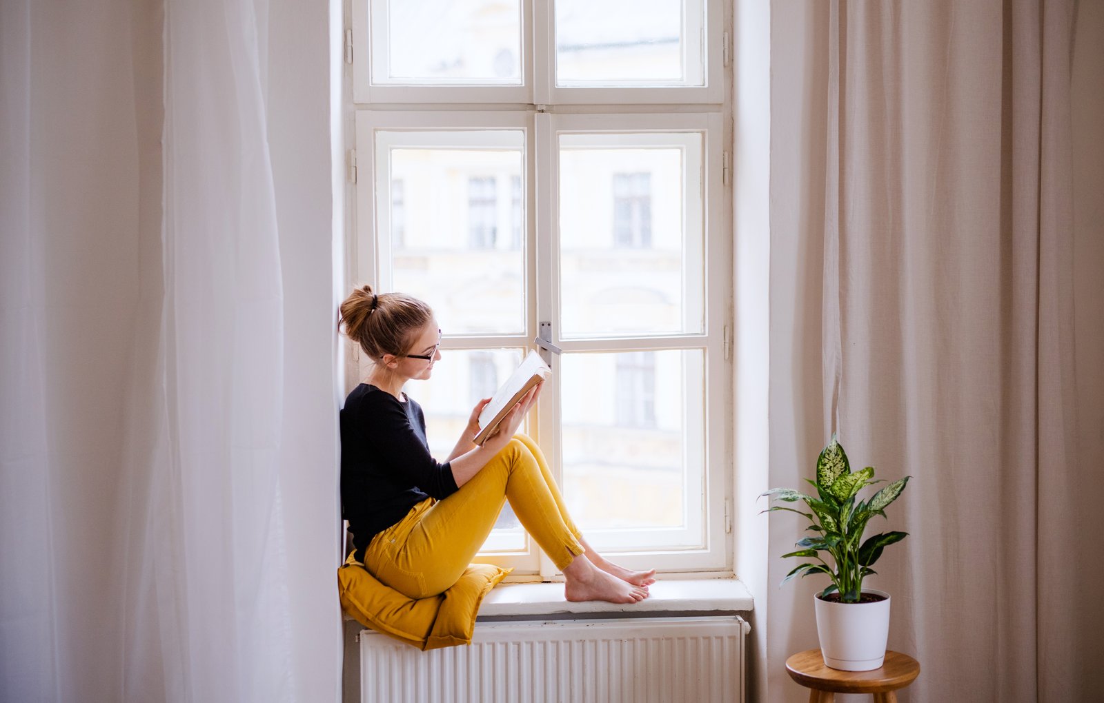 Woman reading a book by a window